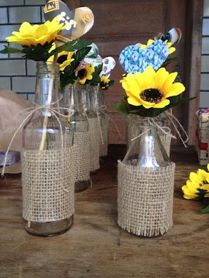 Vasos de garrafas de vidro:  Pegue garrafas de vidro vazias e decore-as com barbantes, sisal ou renda. Coloque flores típicas da época, como girassóis ou margaridas, para enfeitar as mesas e cantinhos da festa.